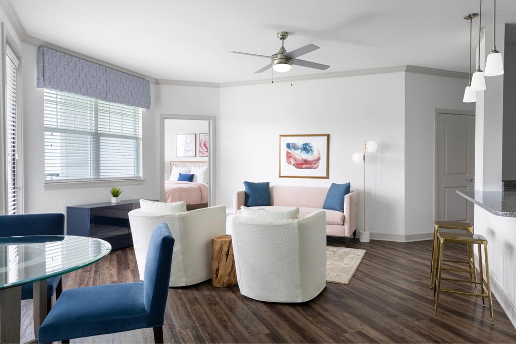 A living room with a white couch, blue chairs, and a ceiling fan.
