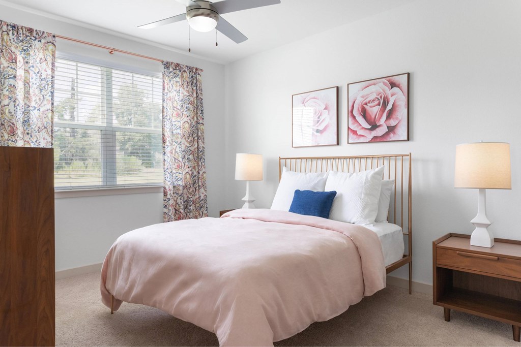 A bedroom with a bed, two lamps, and a ceiling fan.