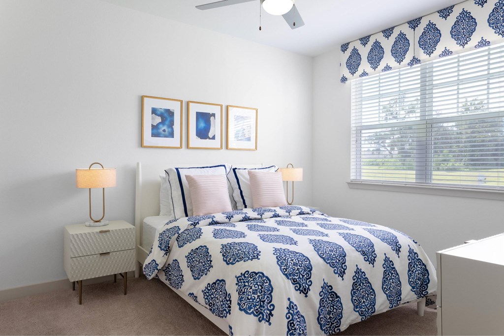 A bedroom with a bed, nightstands, and pictures on the wall.