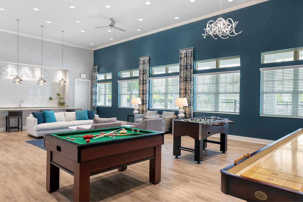 A billiards table is in the middle of a room with a pool table on the right.