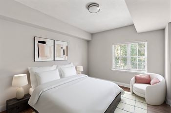 A bedroom with a bed, a chair, and a painting on the wall.