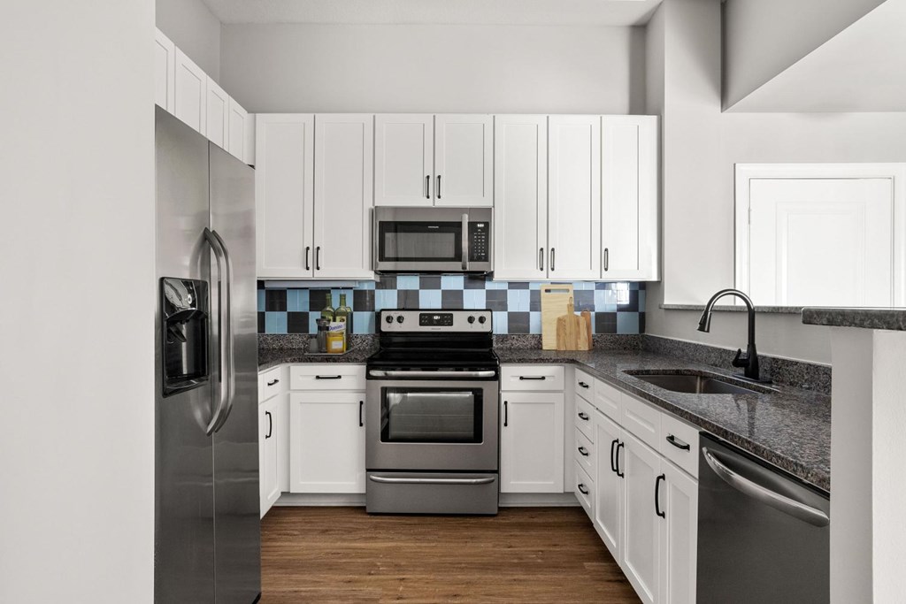 A modern kitchen with white cabinets and stainless steel appliances.