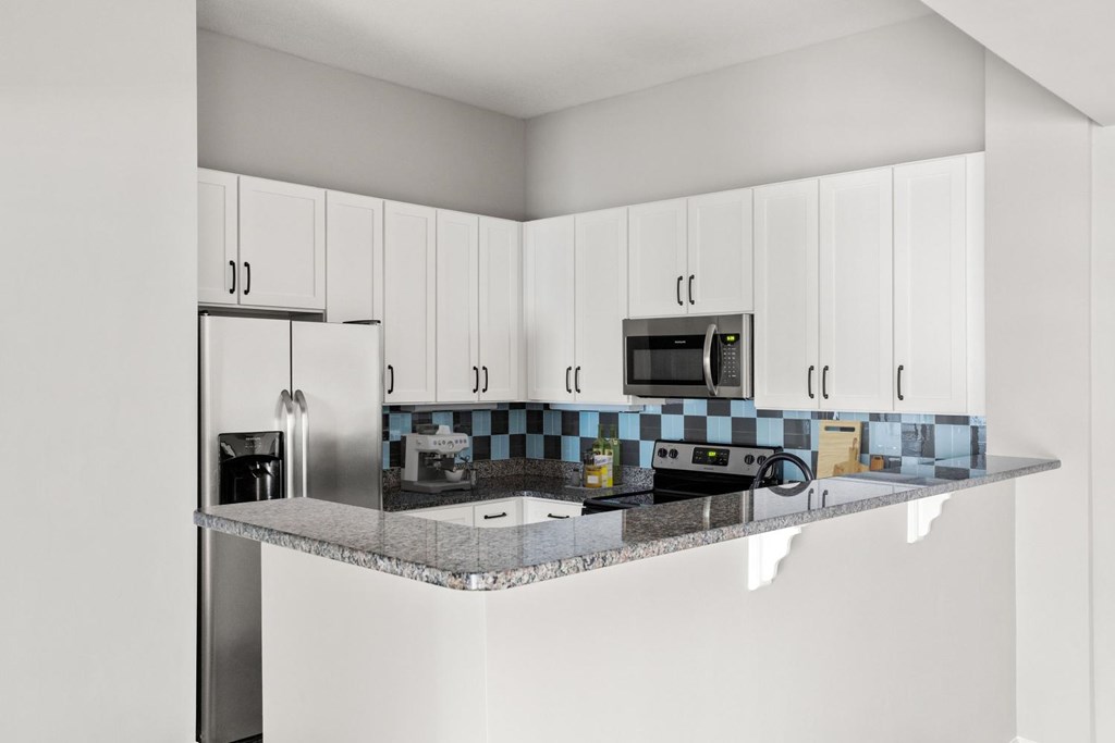 A kitchen with white cabinets and a checkered backsplash.