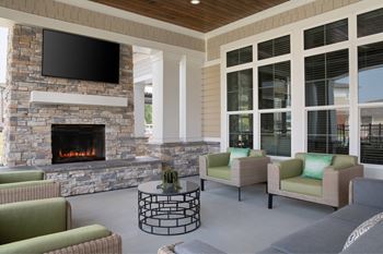 A living room with a stone fireplace and a flat screen TV mounted above it.