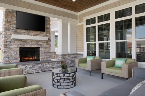 A living room with a stone fireplace and a flat screen TV mounted above it.