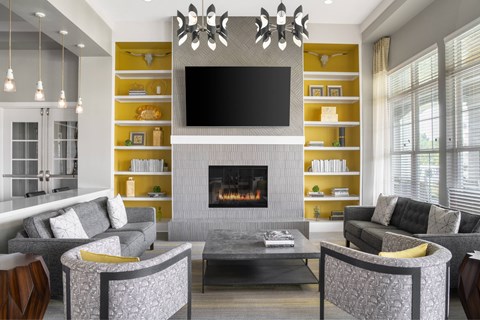 A modern living room with a grey fireplace and a television mounted above it.
