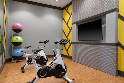 A Spinning bike is in the foreground of a brightly colored gym.