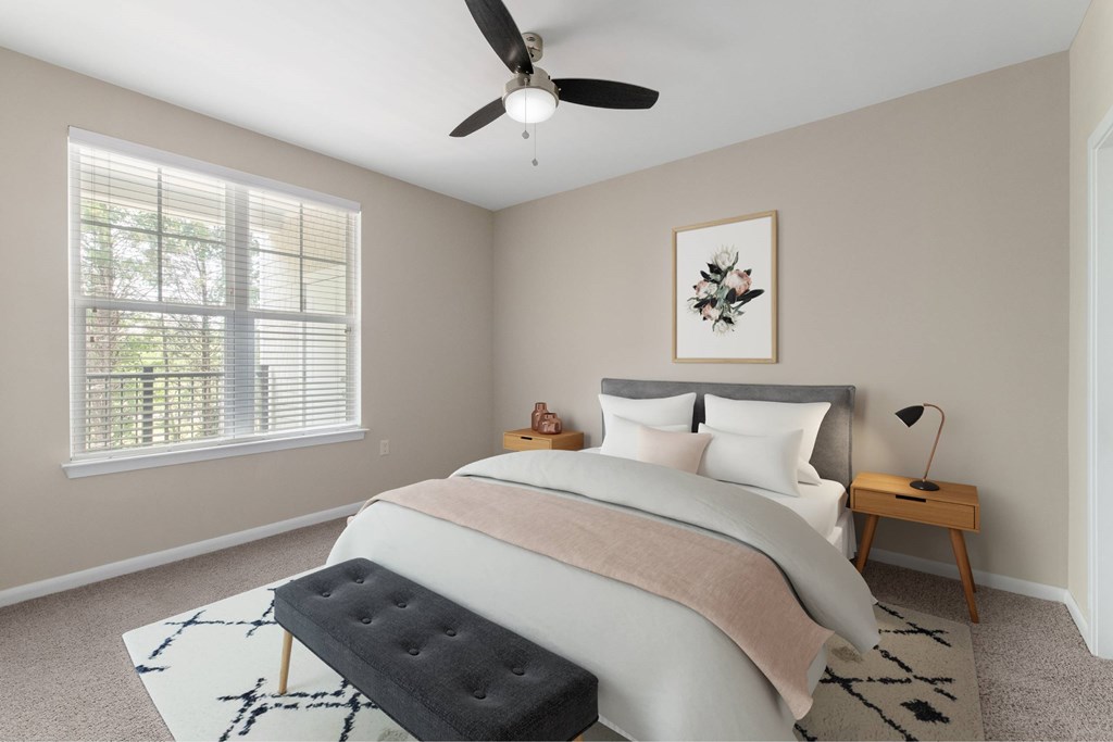 A bedroom with a large bed, a ceiling fan, and a window with blinds.