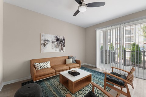 A living room with a brown couch, a coffee table, and a ceiling fan.