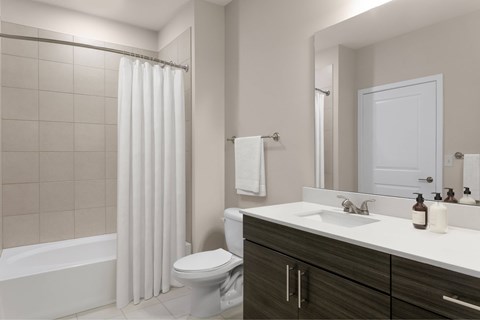 A white bathroom with a toilet, sink, and shower.