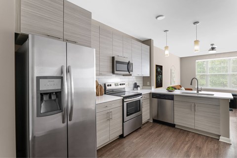 A modern kitchen with stainless steel appliances and wooden flooring.