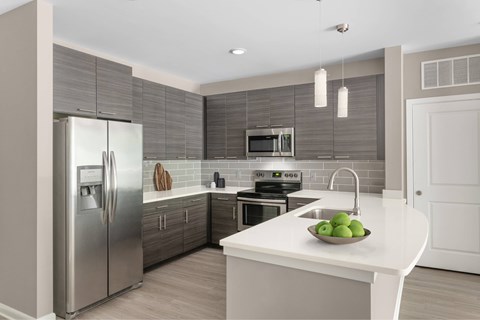 A modern kitchen with a stainless steel refrigerator and a white countertop.