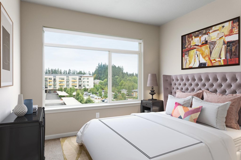 A bedroom with a large bed and a view of a residential area outside the window.