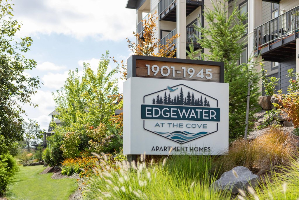 A sign for Edgewater at the Cove Apartment Homes is displayed in front of a building.