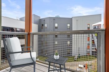 A balcony with a chair and table overlooking a building.