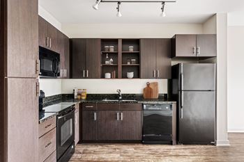 A kitchen with dark wood cabinets and black appliances.