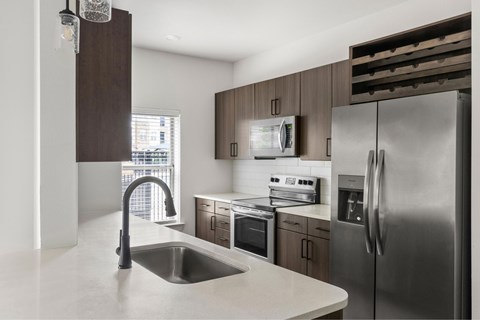 A modern kitchen with a stainless steel refrigerator and a sink.