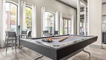 A pool table in a room with a view of the street outside.