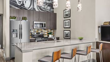 A modern kitchen with a refrigerator, microwave, oven, and sink.