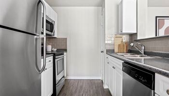 A modern kitchen with a stainless steel refrigerator and white cabinets.