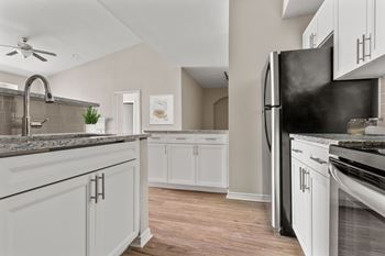 A kitchen with white cabinets and a black refrigerator.