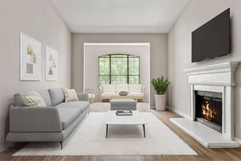 A living room with a grey couch, a coffee table, a fireplace, and a flat screen TV mounted on the wall.