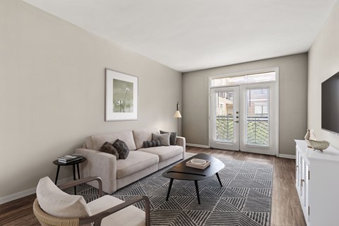 A living room with a grey sofa, a black coffee table, a white chair, and a television.