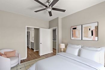 A bedroom with a white bed and a ceiling fan.