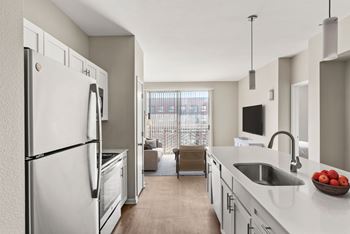 A modern kitchen with a refrigerator, sink, and a bowl of apples on the counter.
