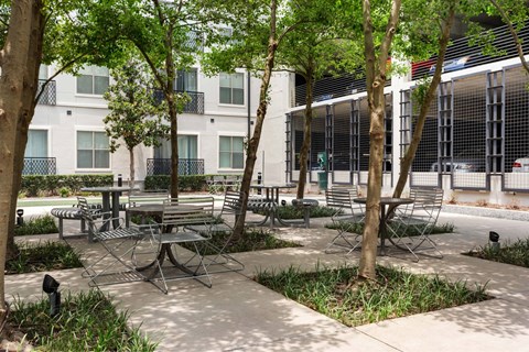 A patio with a table surrounded by chairs and trees.