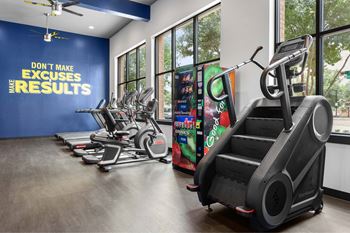 A gym with a row of treadmilers and elliptical machines.