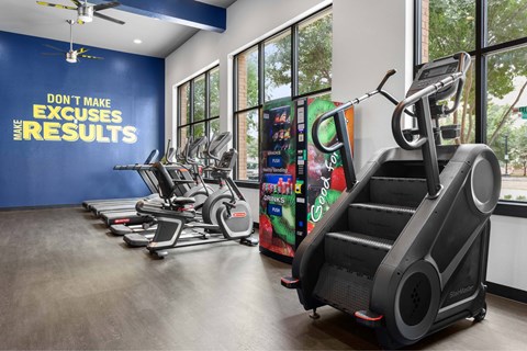 A gym with a row of treadmilers and elliptical machines.