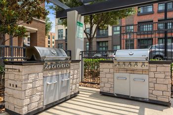 Two stone BBQs are in a sunny courtyard.