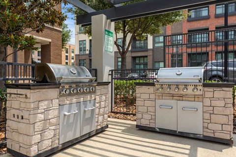 Two stone BBQs are in a sunny courtyard.