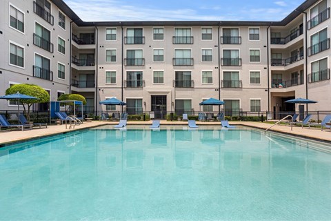 A large swimming pool in front of a multi-story apartment building.