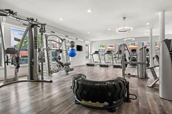 A gym with a variety of equipment including treadmills, weights, and exercise machines.