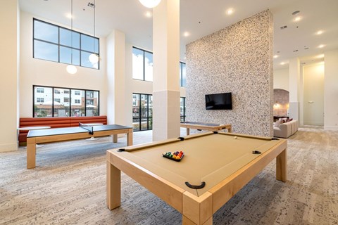 A pool table in a room with a TV and a bench.