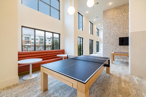 A ping pong table is in the middle of a room with a red couch and a television.