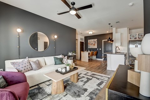 A modern living room with a white couch and a round mirror on the wall.