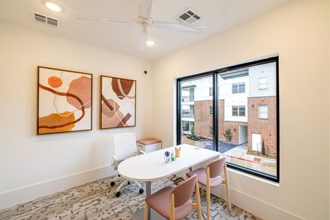 A room with a table and chairs and two paintings on the wall.