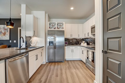 A modern kitchen with stainless steel appliances and wooden floors.