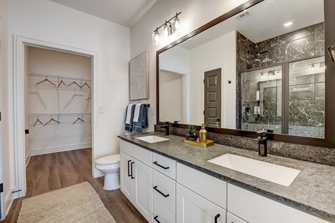 A bathroom with a toilet, sink, and mirror.