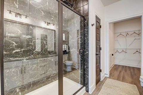 A bathroom with a marble tile wall and a walk-in shower.