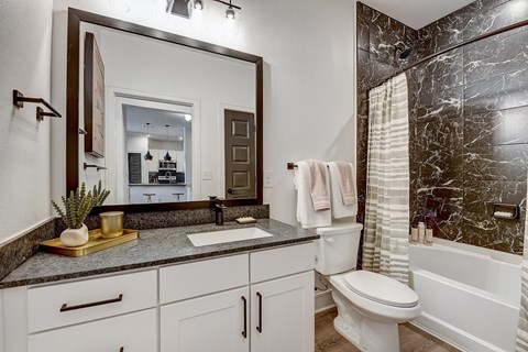 A bathroom with a marble wall and a white toilet.