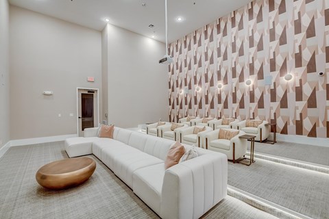 A white couch with a brown ottoman in front of a wall with a geometric pattern.