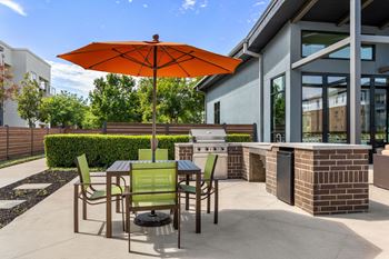 A patio with a table and chairs under an orange umbrella.