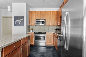 A kitchen with wooden cabinets and a stainless steel refrigerator.