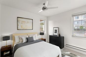 A bedroom with a bed, nightstand, and a painting on the wall.