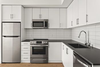 A modern kitchen with a stainless steel refrigerator, oven, and microwave.