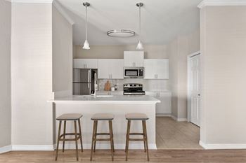 A kitchen with a white countertop and bar stools.